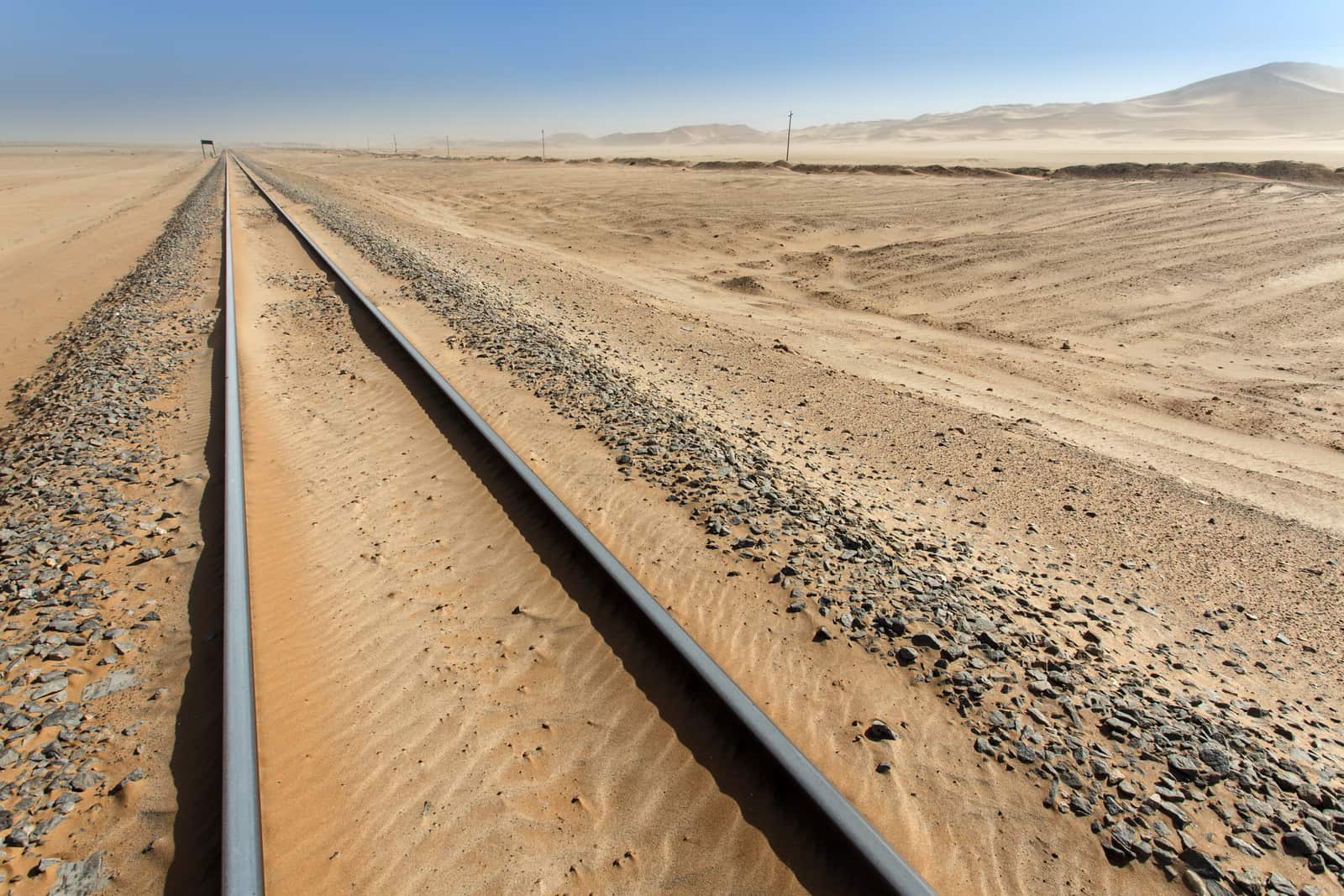 Ein Bahngleis im Sand vor hellen Dünen