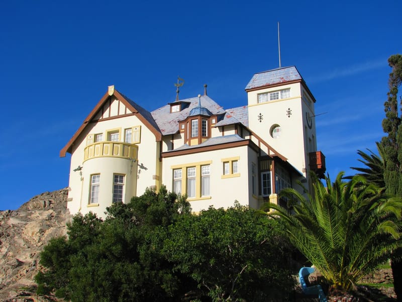 Jugendstilvilla mit Turm am Hang, davor Palmen